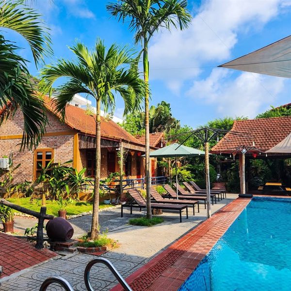 Hồ bơi và dãy nhà gạch mái ngói trong khuôn viên — Trang An Village Homestay