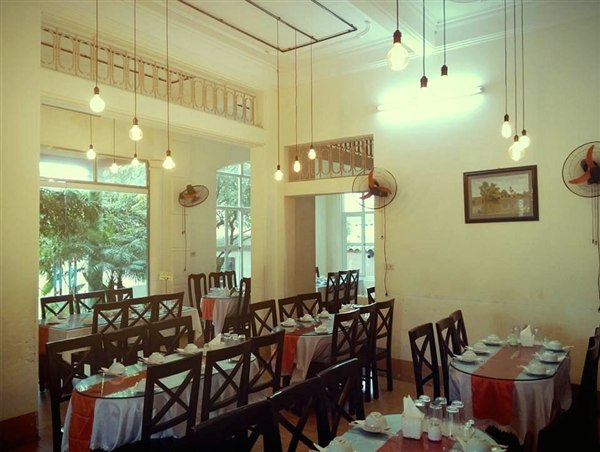 Phòng ăn trong nhà hàng Thăng Long ngày trước: bàn ghế gỗ, khăn trải trắng, đèn dây thả từ trần cao